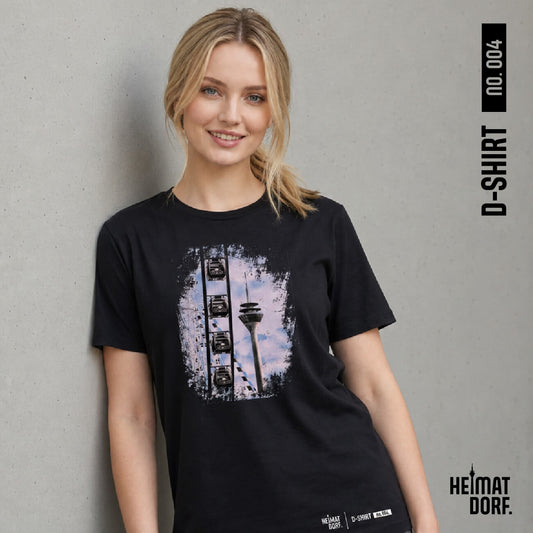Junge, blonde Frau trägt ein schwarzes Düsseldorf T-Shirt mit Rheinturm und Riesenrad-Motiv als Aufdruck als Hommage an die Rheinkirmes. Das T-Shirt ist das Motiv No. 004 der D-Shirt Kollektion.