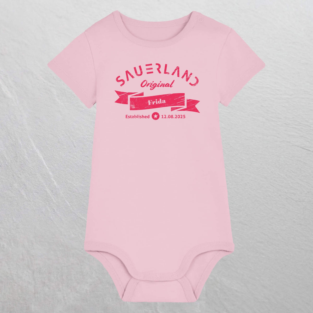 Rosa farbiger Baby-Body mit pinkfarbigem Aufdruck Sauerland Original, dem Vornamen und Geburtsdatum des Babys.