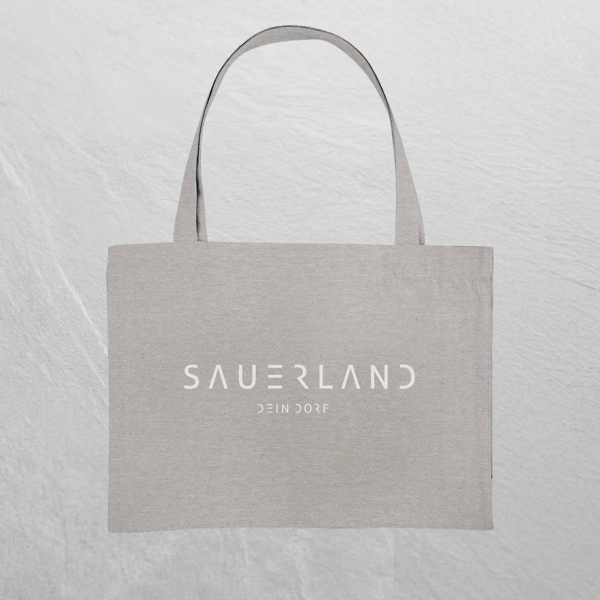Graue Baumwolltasche mit weißem Sauerland Logo bedruckt. Der moderne Schriftzug wird darunter mit dem Dorfnamen ergänzt. 