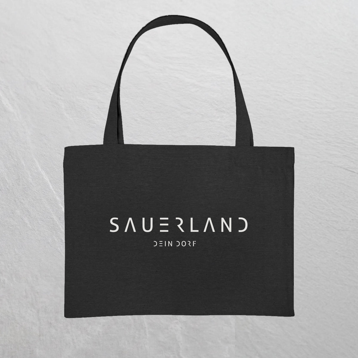 Schwarze Baumwolltasche mit weißem Sauerland Logo bedruckt. Der moderne Schriftzug wird darunter mit dem Dorfnamen ergänzt. 