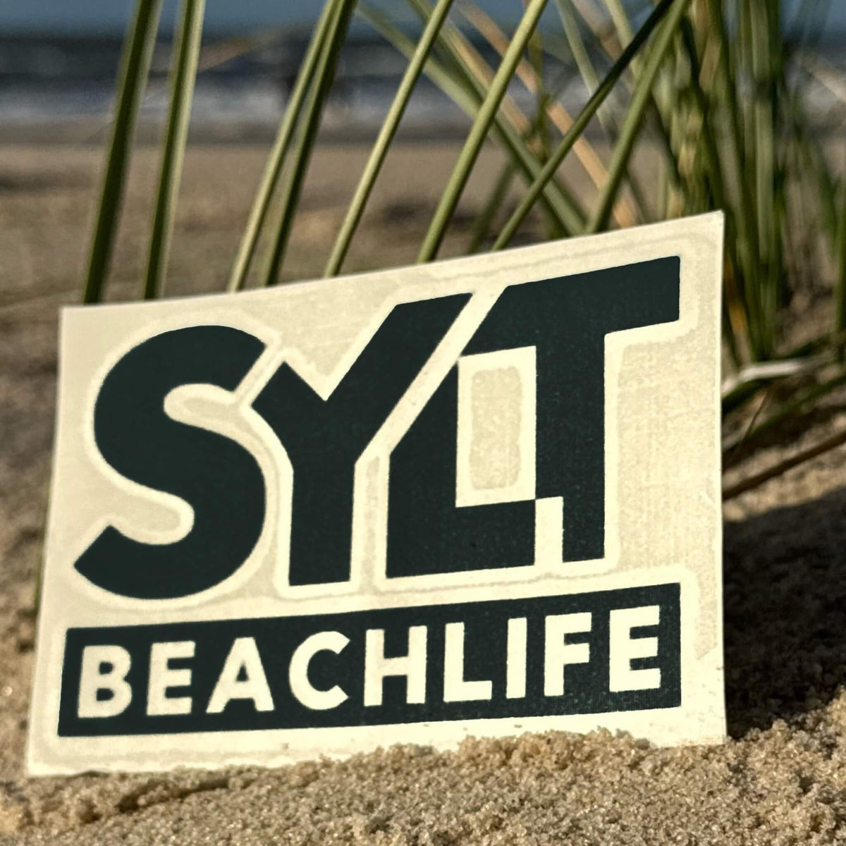 Sylt Aufkleber Beachlife in schwarz liegt an einem Strand