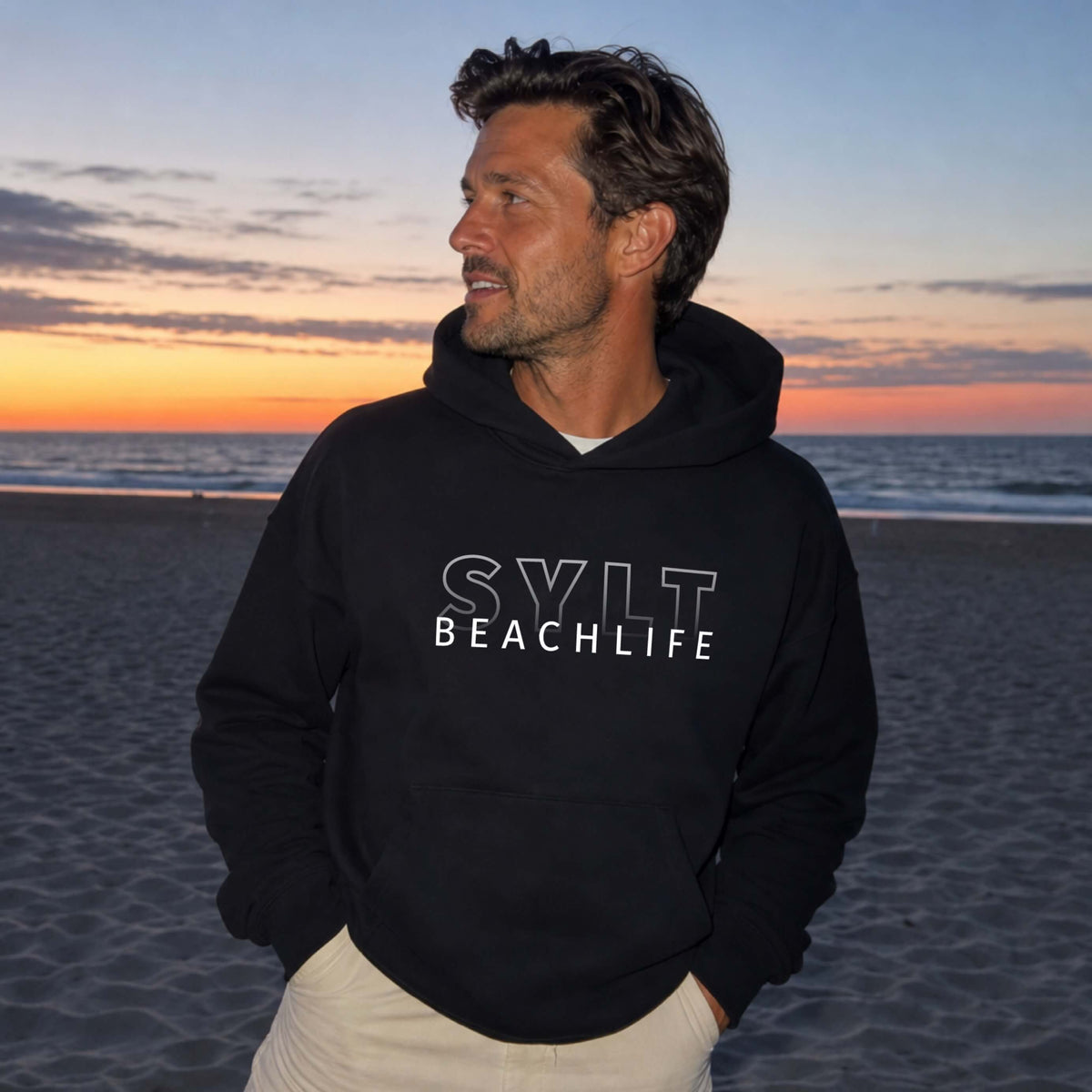 Mann steht auf Sylt am Strand mit einem schwarzen BEACHLIFE SYLT Gradient Hoodie
