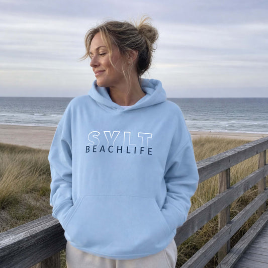Frau steht auf Sylt am Strand mit einem hellblauem  BEACHLIFE SYLT Gradient Hoodie