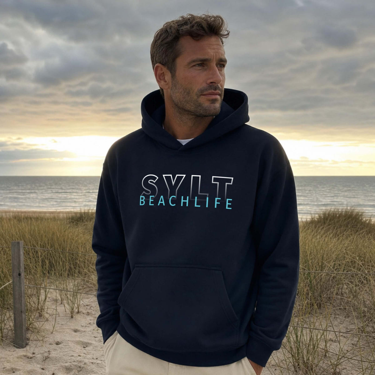 Mann steht auf Sylt am Strand mit einem dunkelblauen BEACHLIFE SYLT Gradient Hoodie