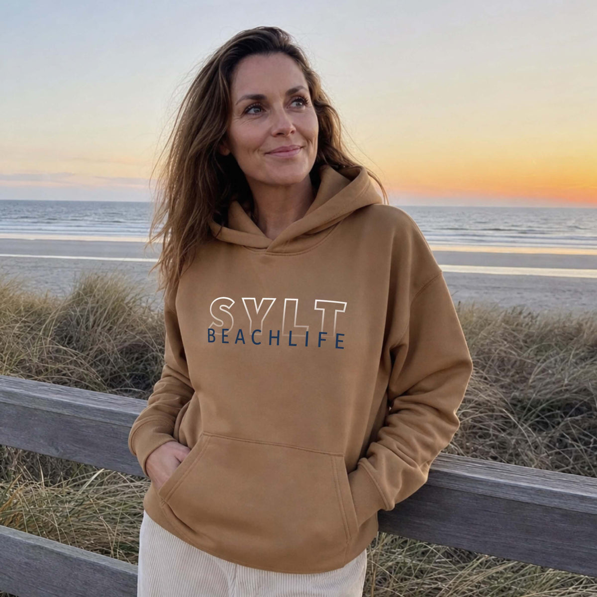 Frau steht auf Sylt am Strand mit einem reed farbigen BEACHLIFE SYLT Gradient Hoodie