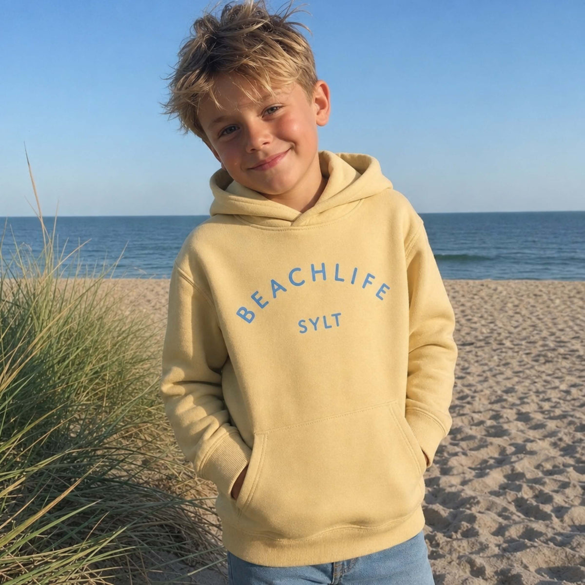 Kind am Strand mit gelben BEACHLIFE SYLT Hoodie